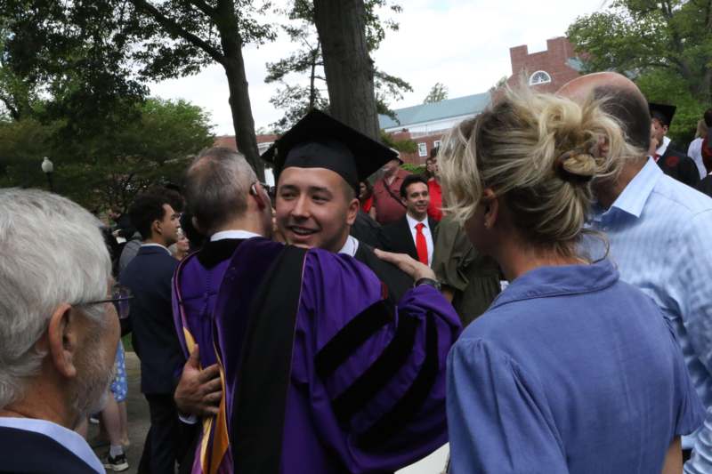 a man in a graduation gown hugging a woman