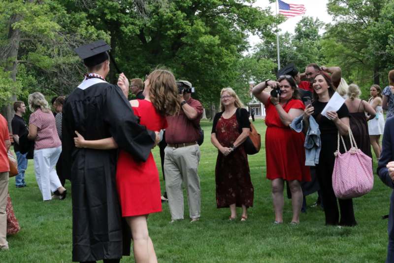 a man in a graduation gown hugging a group of people