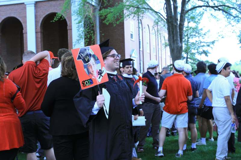 a man in a graduation gown holding a sign