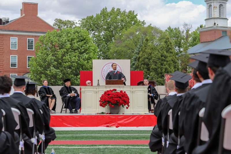a man standing in front of a podium with people in gowns