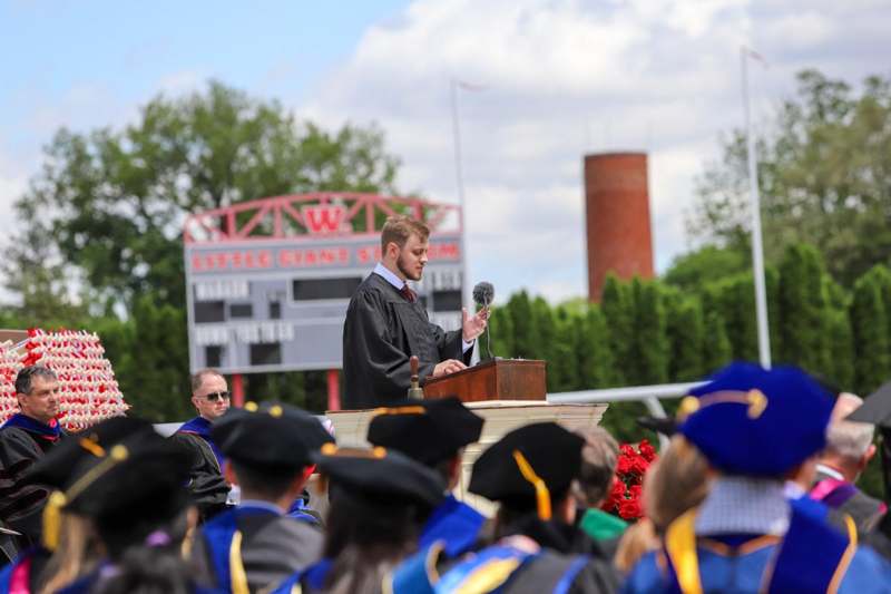 a man in a black robe speaking at a podium with a microphone
