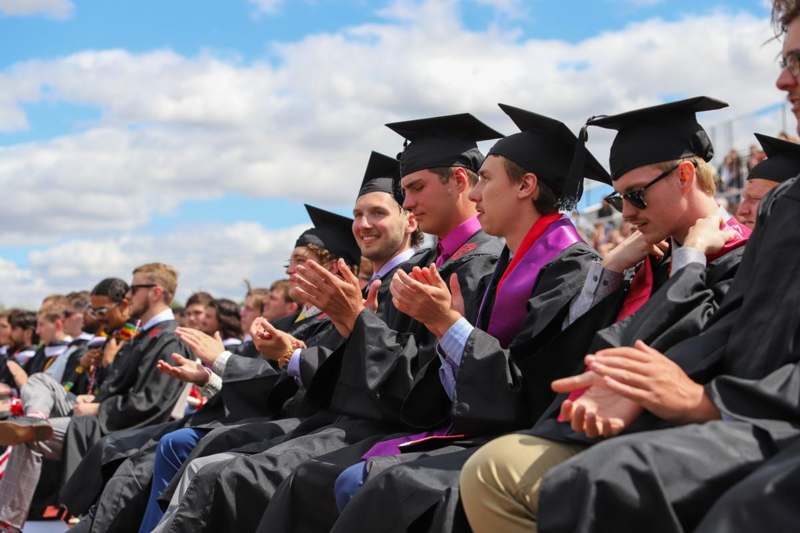a group of people in graduation gowns and caps clapping