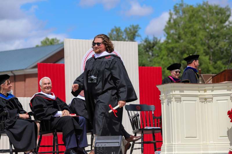 a man in a black robe and sunglasses standing in front of a podium
