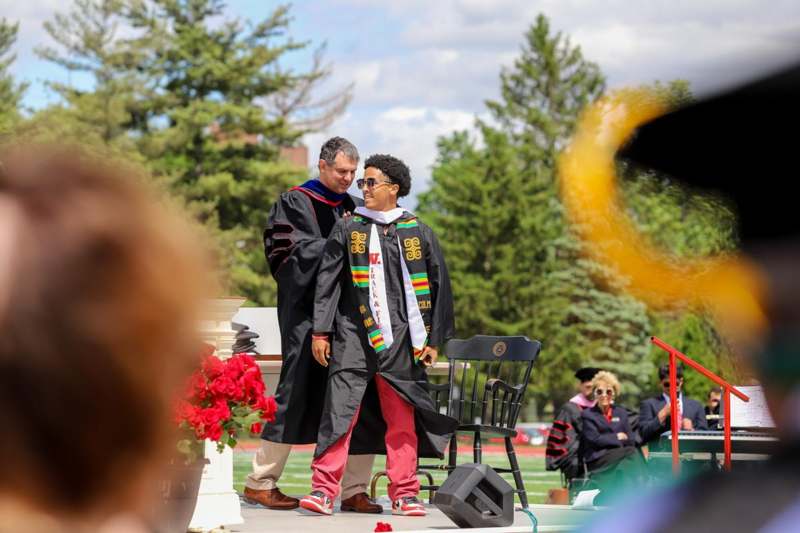 a man in a black robe hugging another man in a black robe