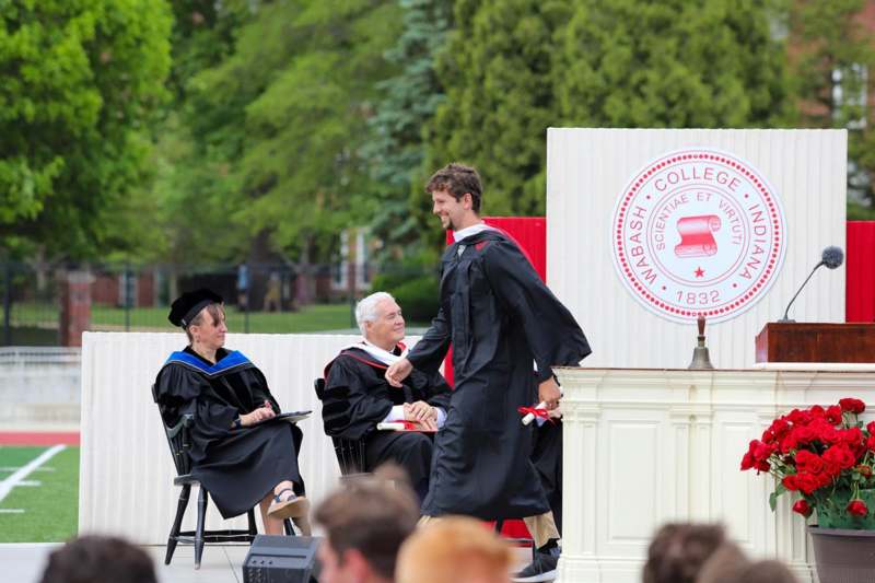 a man in black gown shaking hands with a man in black gown