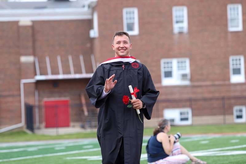 a man in a graduation gown waving