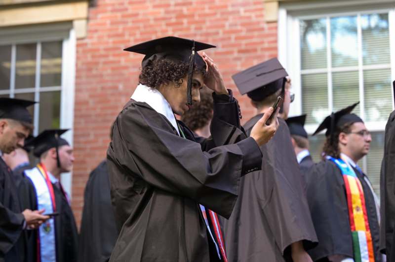a man in a graduation gown holding his head