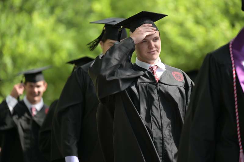 a man in a graduation gown saluting
