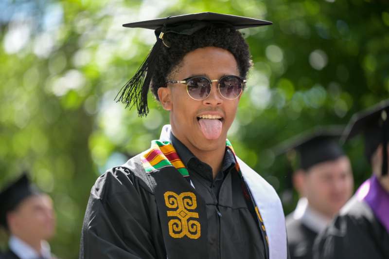 a man wearing a graduation gown and cap sticking his tongue out