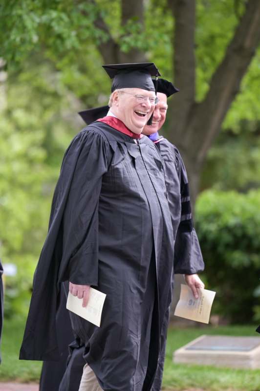 a man in a graduation gown and cap laughing
