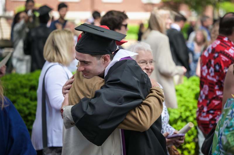 a man in a graduation gown hugging another man