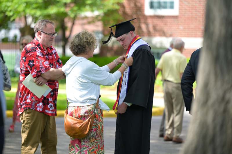 a woman putting a graduation cap on a man