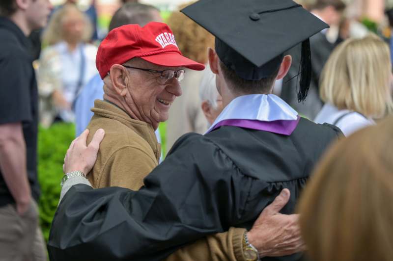 a man in a cap and gown hugging another man