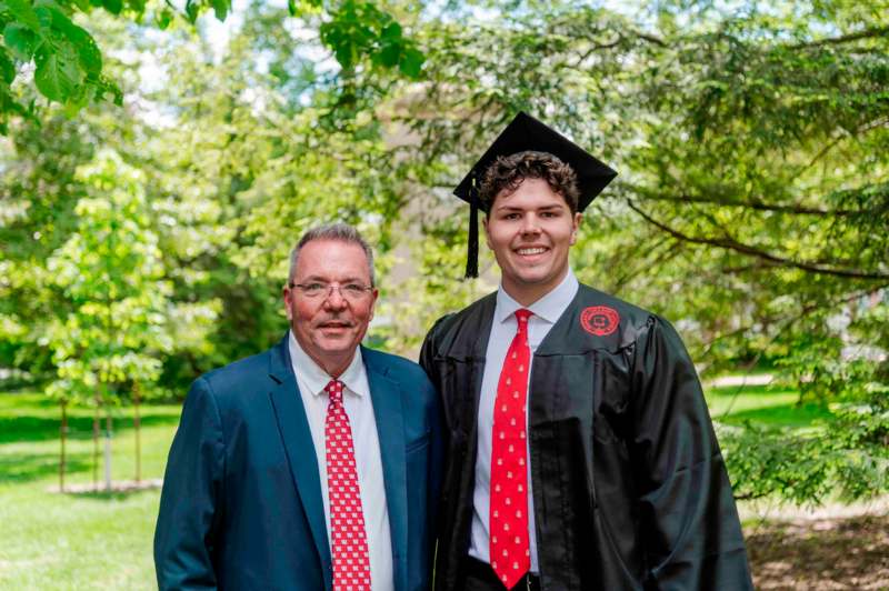 a man in a cap and gown standing next to a man in a suit