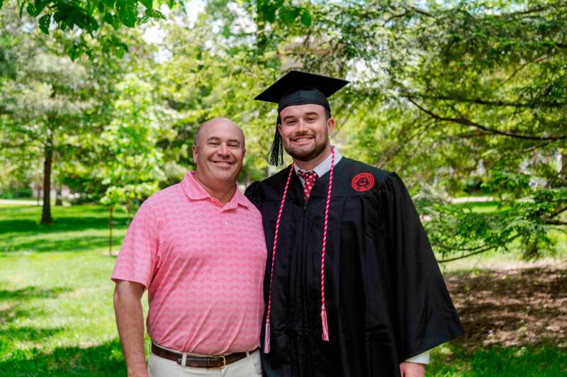 a man in a cap and gown standing next to a man in a cap and gown