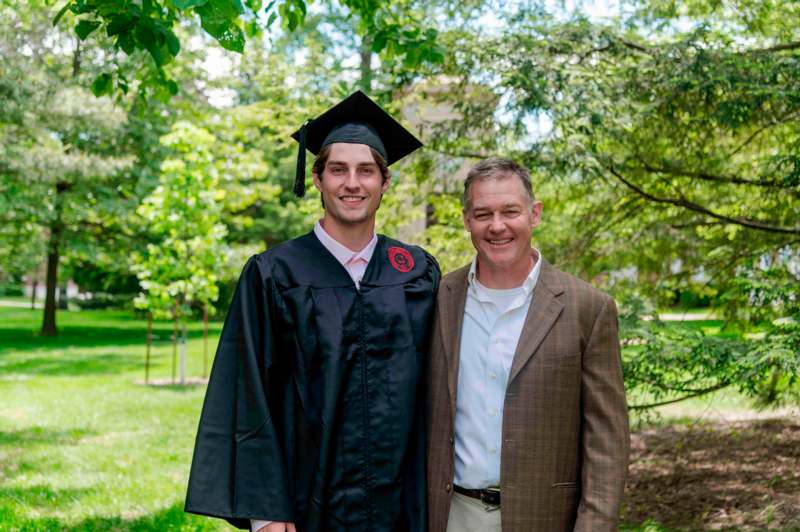 a man in a cap and gown standing next to a man in a suit