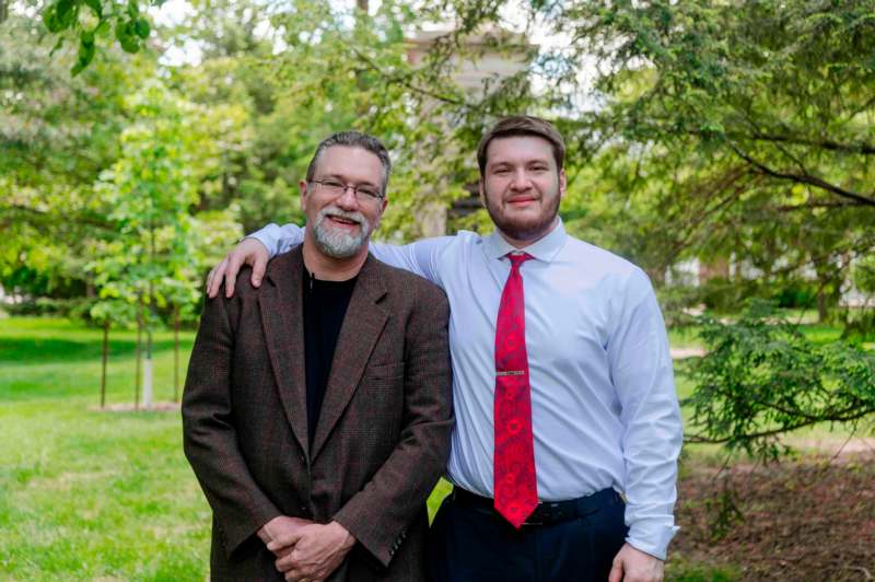 two men standing together in a park