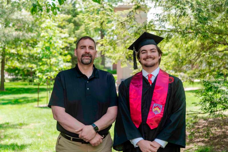 a man standing next to a man in a graduation gown