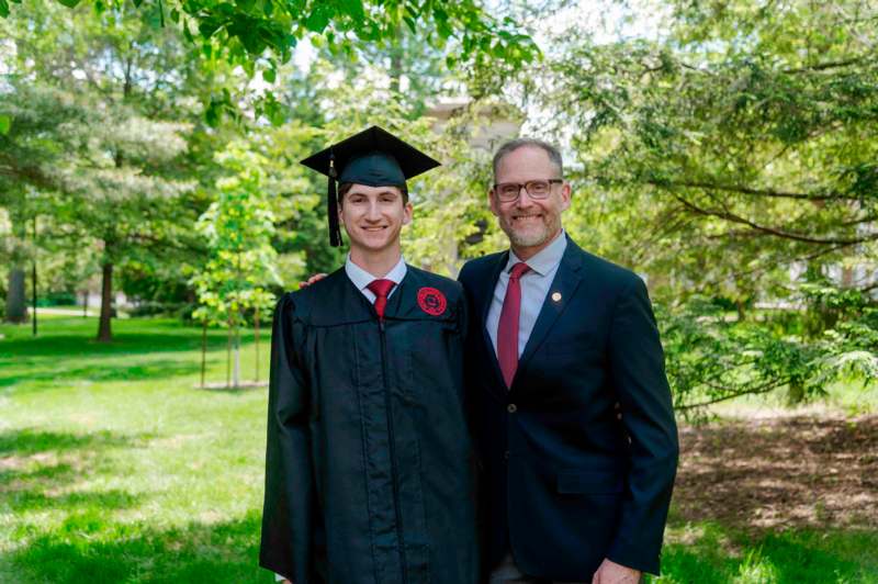a man in a cap and gown standing next to a man in a suit