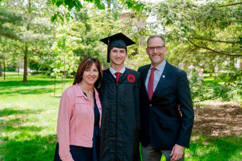a man in a cap and gown with a woman and man in a suit