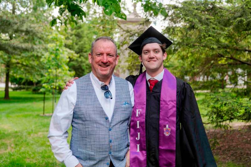 a man in a graduation cap and gown posing for a picture
