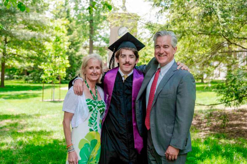 a man and woman standing in a graduation gown and cap
