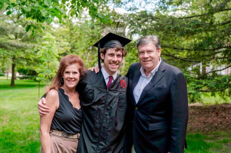 a man in a cap and gown with a man and woman in a park