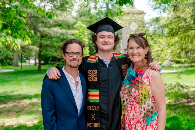 a man in a graduation cap and gown with a woman in a park