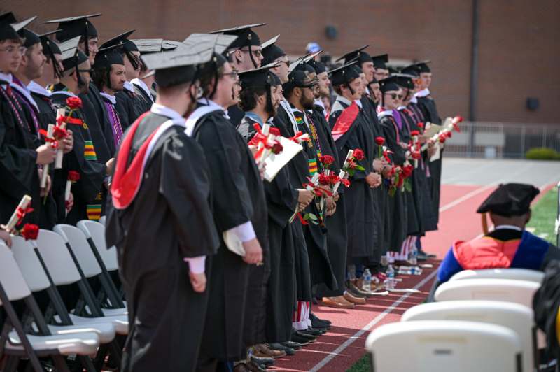 a group of people in graduation gowns holding flowers