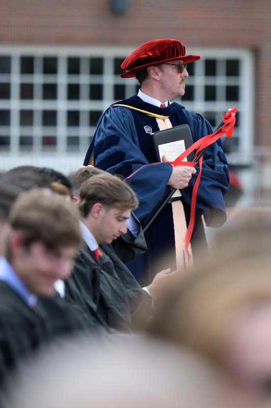 a man in a robe holding a book and standing in front of a crowd