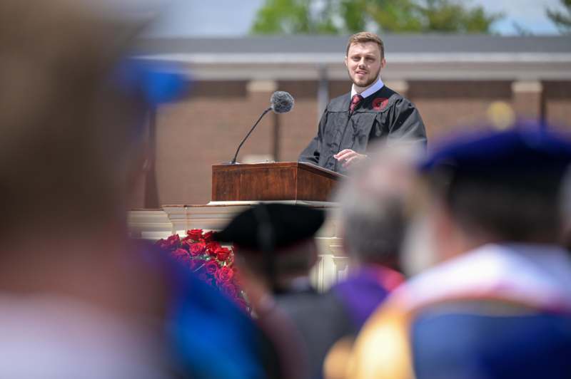 a man in a graduation gown standing at a podium