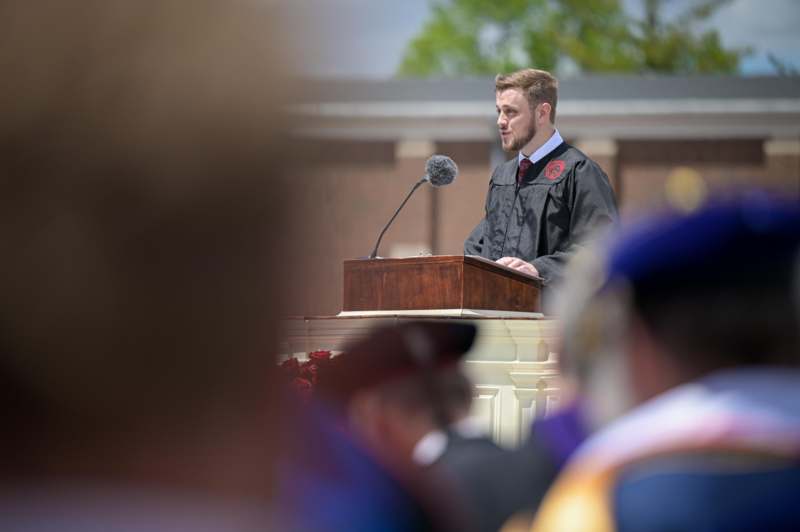 a man in a graduation gown standing at a podium