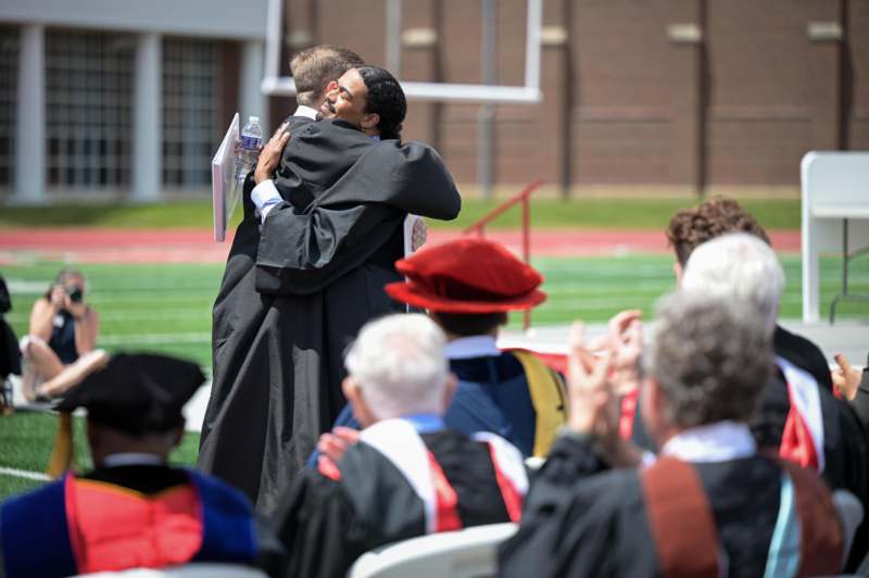 a man hugging another man in a graduation gown