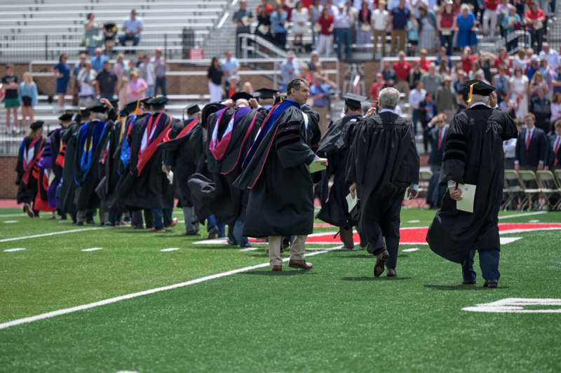 a group of graduates walking on a field
