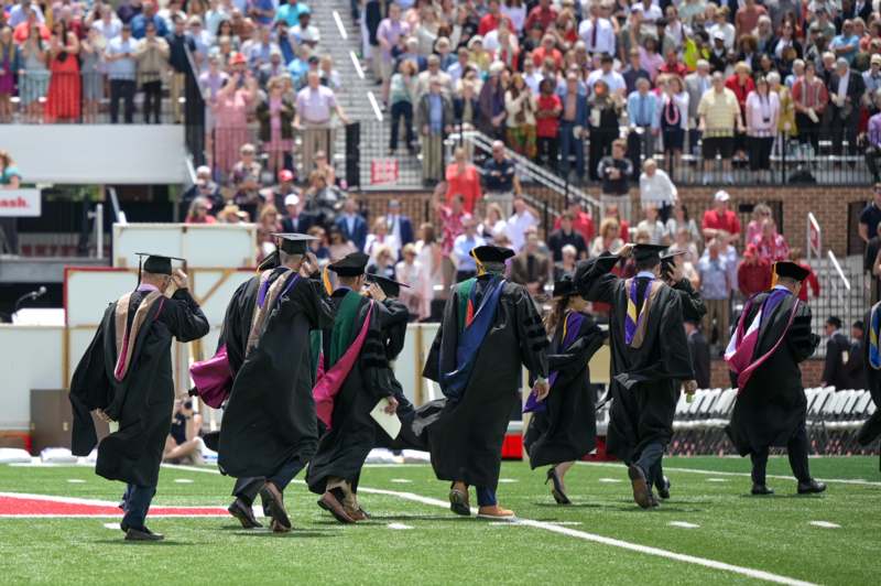 a group of graduates walking on a football field