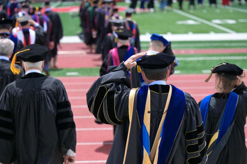 a group of people in graduation gowns saluting