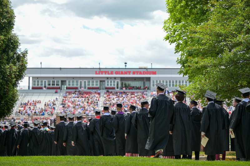 a group of graduates in black gowns and caps standing in a line