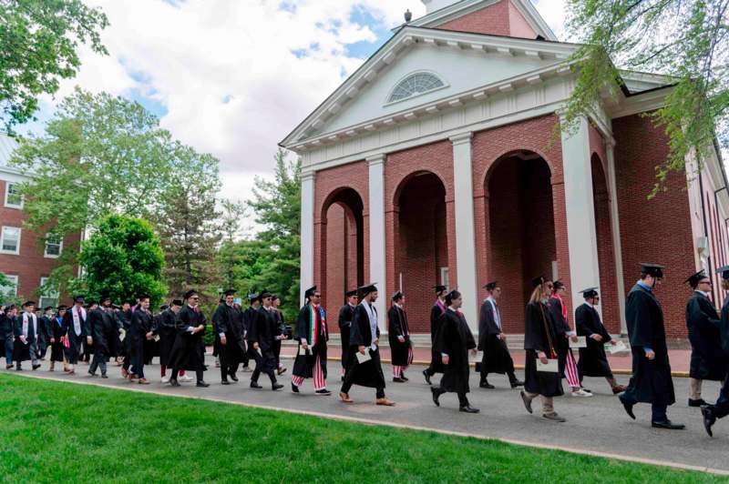 a group of people in graduation gowns walking outside a building