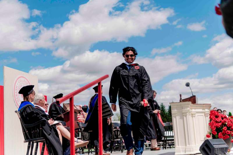 a man in a graduation gown walking down a stage