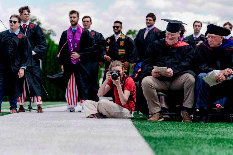 a man in a graduation gown taking a picture of a woman