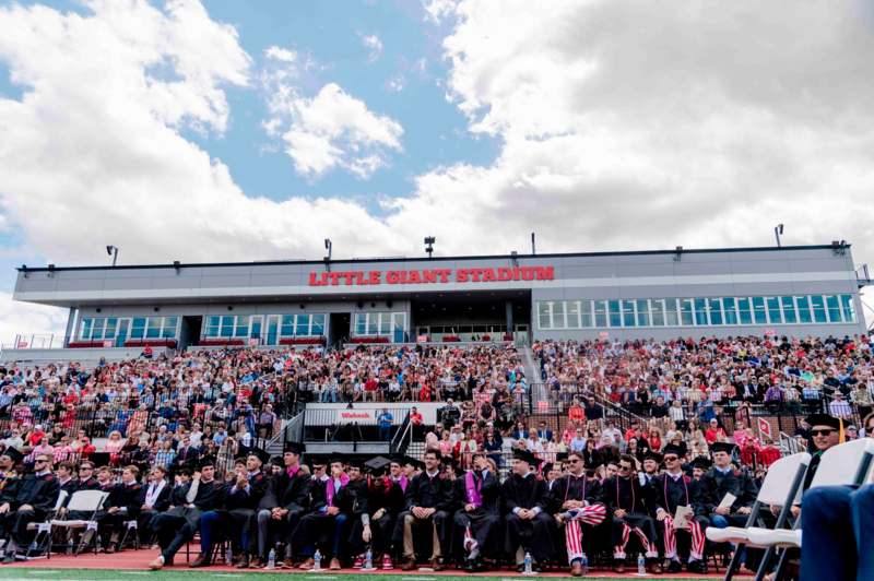 a group of people in graduation gowns sitting in a stadium