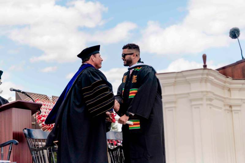 a man in black robe shaking hands with another man in black robe