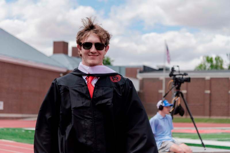 a man wearing a graduation gown and sunglasses