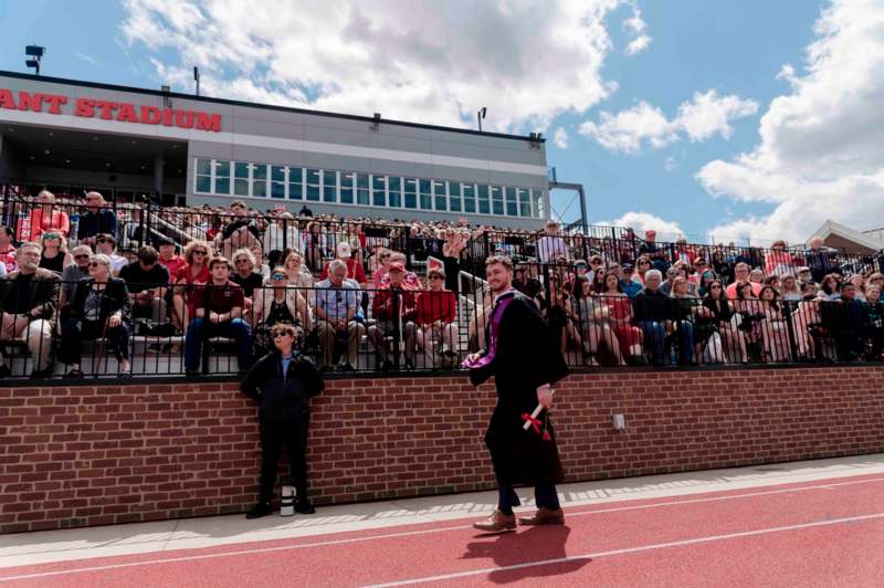 a man in a robe walking on a track with a crowd watching