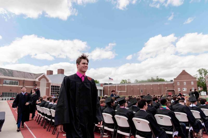 a man in a graduation gown standing in front of a group of people