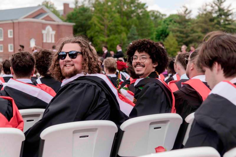 a group of men in graduation gowns sitting in chairs