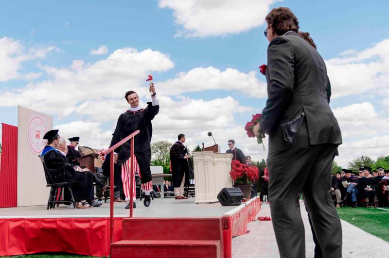 a man in a black robe waving his hand to a man in a black robe