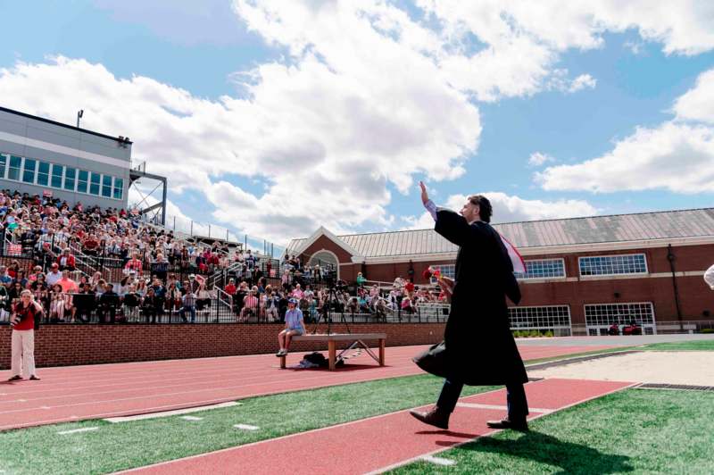 a man in a black robe waving his hand