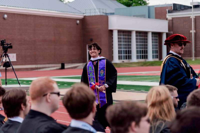 a man in a graduation gown standing in front of a group of people