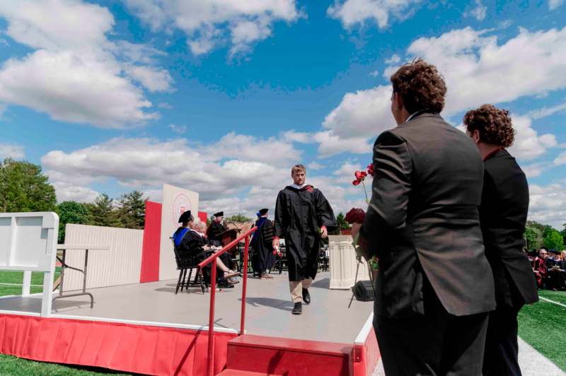a man in a black gown walking on a stage